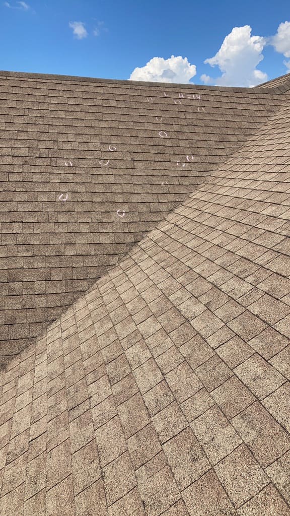 Roof slope with numerous chalk-circled hail hits marked during an inspection